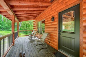 Une cabane en bois dotée d’une véranda, de fauteuils à bascule et d’une porte avec une fenêtre.