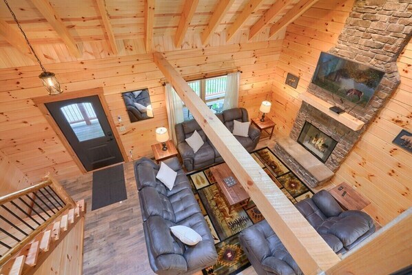 A cozy cabin interior with a fireplace, wooden walls, and a sofa area.
