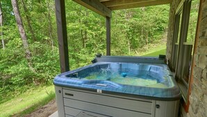 Ein Whirlpool in einem überdachten Außenbereich mit Blick auf einen Wald.