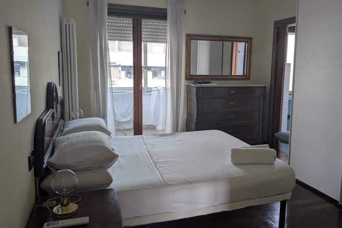 A bedroom with a bed, bedside table, dresser, and a mirror.