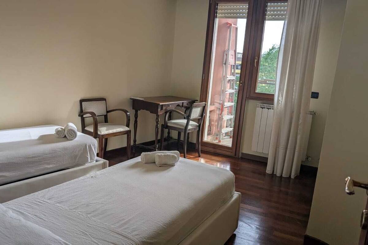 A hotel room with two beds, a desk, and a chair.