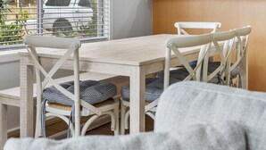 Een eetgedeelte met een houten tafel en witte stoelen, elk met gestreepte kussens.