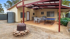 Enjoy al fresco dining and entertainment in this outdoor space, featuring a barbecue grill and ping pong table.