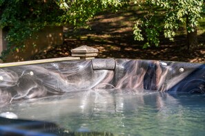 A hot tub with a stone structure on top, surrounded by greenery.