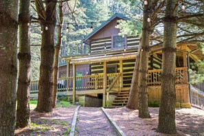 Eine Holzhütte mit einer Holzterrasse und einer überdachten Veranda, umgeben von Bäumen.