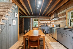 Ein rustikales Blockhaus-Interieur mit einem Holzespeisetisch, Stühlen und einer Küchenzeile mit modernen Geräten.