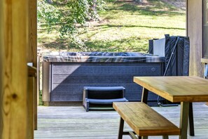 Ein Whirlpool auf einer Holzterrasse mit einer Bank und einem Tisch in der Nähe.