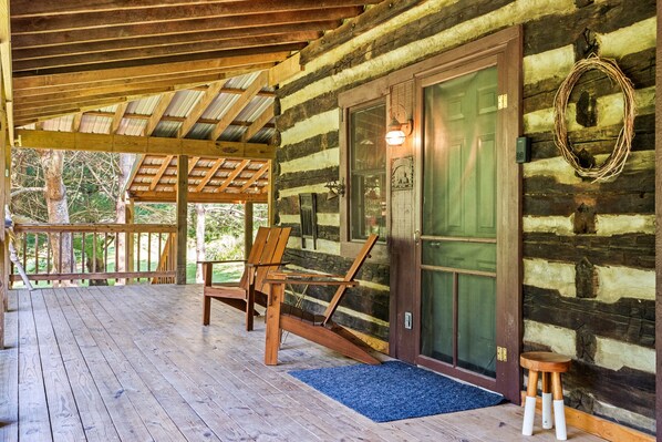 Eine Blockhütte mit einer Holzveranda, einer grünen Tür und einem Kranz an der Wand.