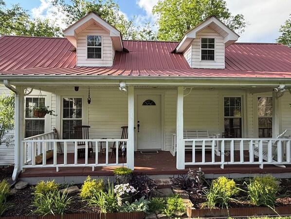 A two-story house with a porch, a front door, and a small window.