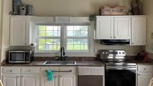 A kitchen with white cabinets, a stainless steel microwave, a sink, a stove, and a dishwasher.