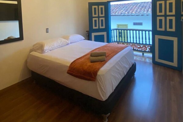 A bedroom with a bed, a window, and a balcony.