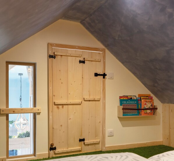 A room with a wooden door, a window, and a shelf with books.