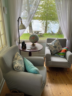 Relax in a serene lakeside retreat with a comfortable seating area, globe, and tranquil view.