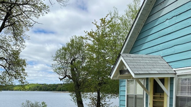 A house with a porch, a small deck, and a view of a lake.