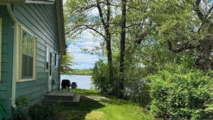 A house with a grassy yard and a view of a lake.