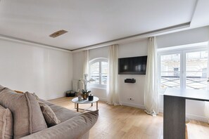 A modern living room with a sofa, a coffee table, and a flat-screen TV mounted on the wall.