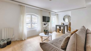 Ein modernes Wohnzimmer mit einer Couch, einem kleinen runden Tisch und einem Fernseher.