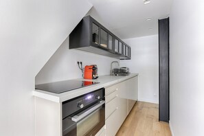 A modern kitchen with a built-in oven, a coffee machine, and a black cabinet above the countertop.