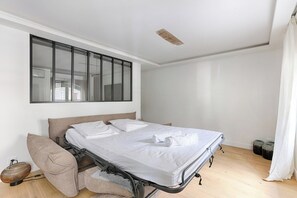 A modern bedroom with a bed, a large window, and a ceiling light fixture.