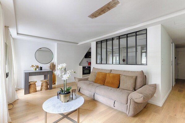 Un salon moderne avec un canapé, une table basse ronde et une grande fenêtre.
