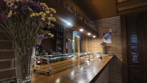 Una zona de bar con un mostrador de madera, un pilar de bronce y un cartel en la pared.