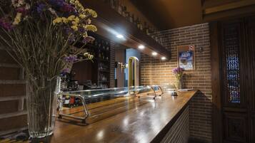 A bar area with a wooden counter, a brass column, and a sign on the wall.