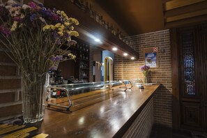 Una zona de bar con un mostrador de madera, un pilar de bronce y un cartel en la pared.