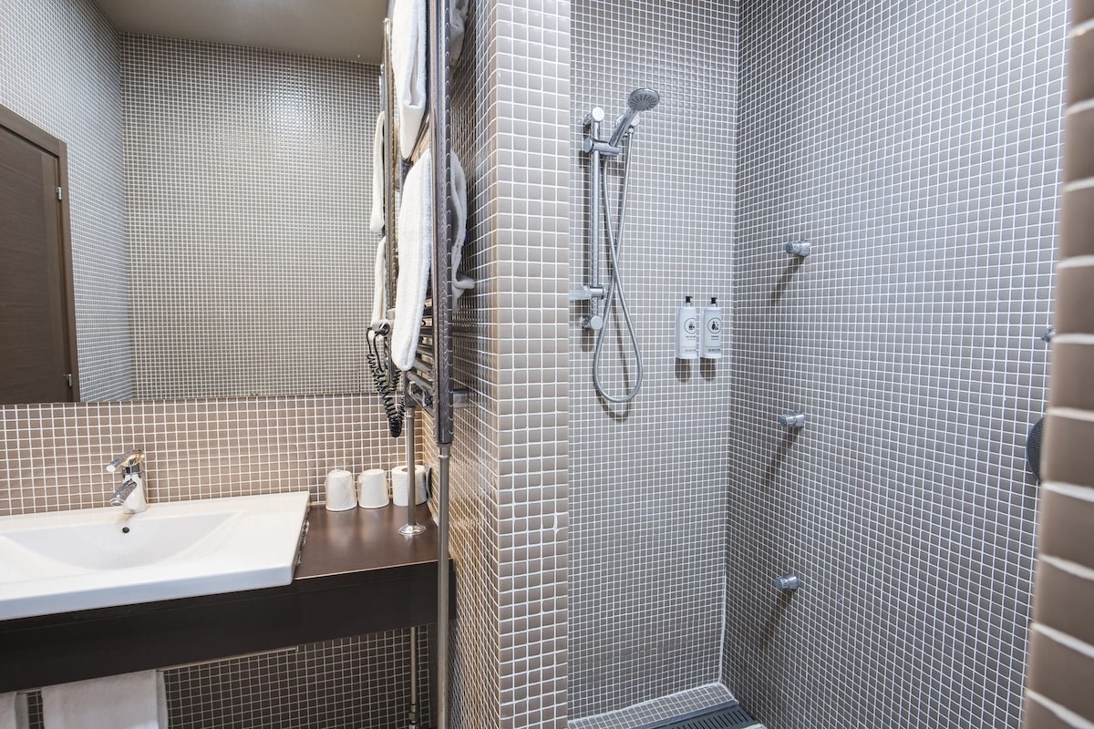A modern bathroom with a tiled shower, a sink, and a mirror.