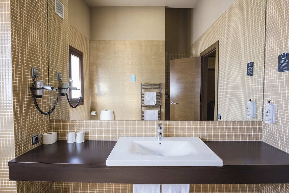 Un baño con un espejo grande, un lavabo y un secador de pelo montado en la pared.