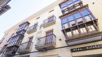 Un edificio con varios balcones, un cartel que dice 'Alda Hotels' y una placa con el número '23'.