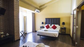 Une chambre d’hôtel avec une cheminée en briques, un grand lit avec des oreillers rouges, une petite table de chevet avec une lampe et une grande fenêtre avec des rideaux.