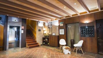 A hotel lobby with a staircase, reception desk, and seating area.