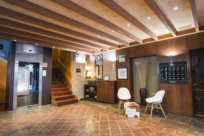 Vestíbulo de hotel con escalera, mostrador de recepción y zona de estar.