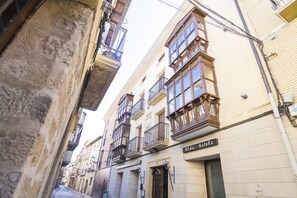 Una stretta via fiancheggiata da edifici con balconi e un cartello con la scritta "Alda Hotels".