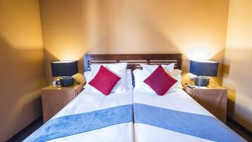 A hotel room with a large bed, two nightstands, and two lamps.