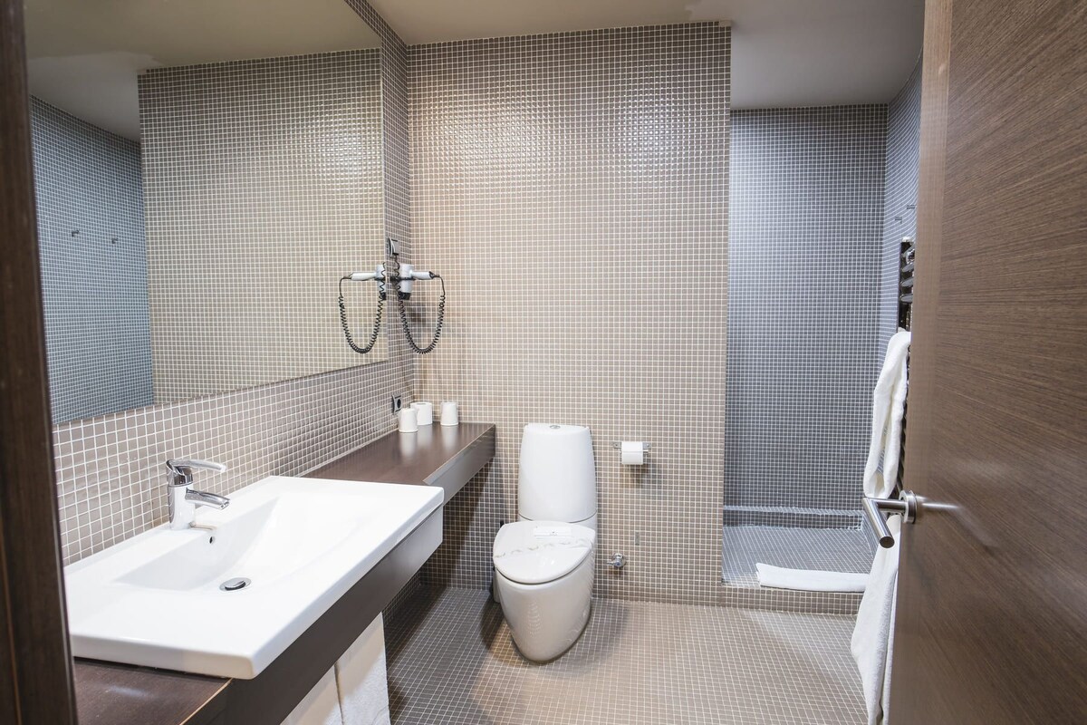 Un baño moderno con lavamanos, inodoro y ducha.