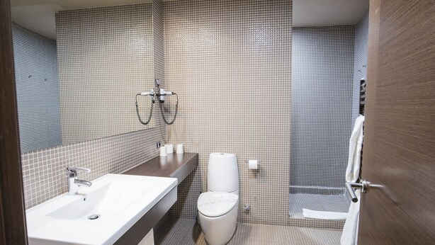 Un baño moderno con lavamanos, inodoro y ducha.