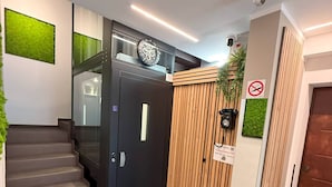 Een modern interieur met een trap, een zwarte deur, een houten lambrisering en een beveiligingscamera.