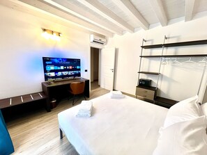 Une chambre d’hôtel comprenant un lit, un bureau avec un ordinateur, une télévision et une armoire.