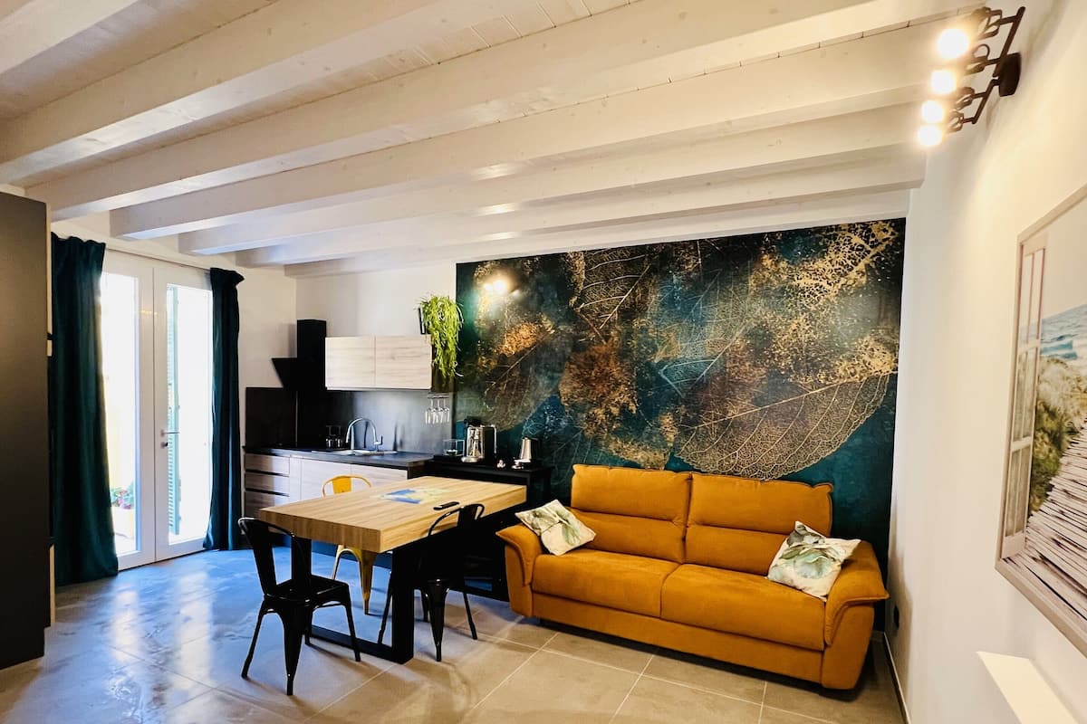 Une cuisine moderne avec un coin repas, comprenant une table en bois, des chaises noires et un canapé de couleur moutarde.