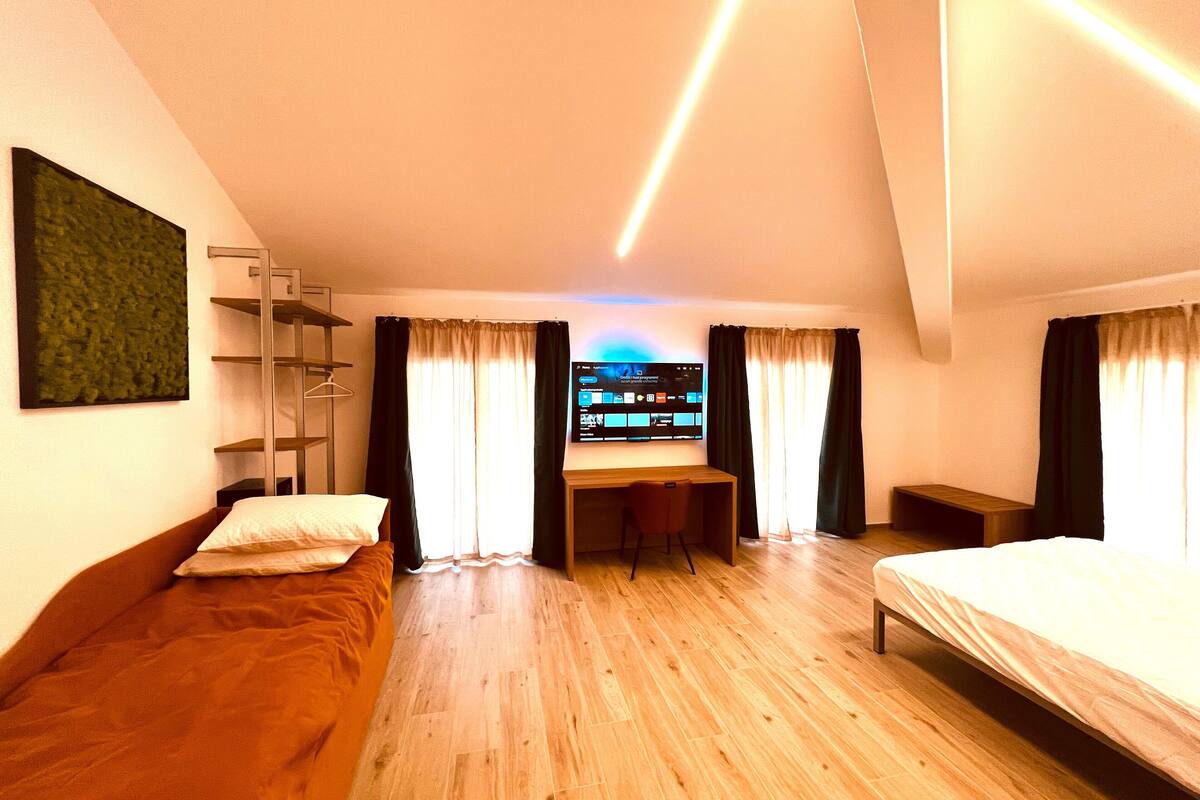 Une chambre d’hôtel moderne avec un plancher en bois, un lit, un bureau et une télévision.