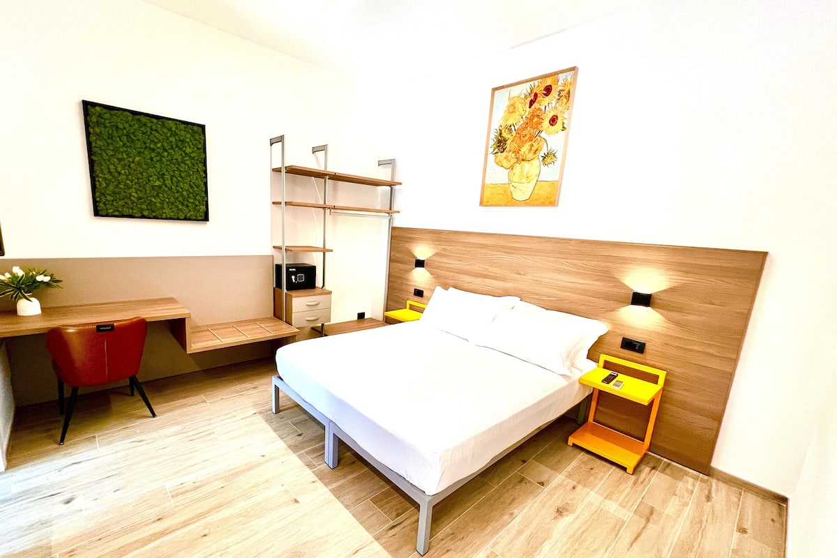 Une chambre d’hôtel moderne équipée d’un lit, d’un bureau, d’une chaise et de tables de chevet.