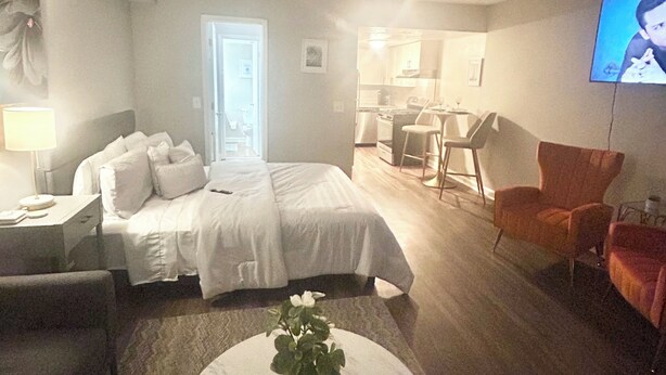A hotel room with a bed, a desk, a chair, a TV, and a coffee table.