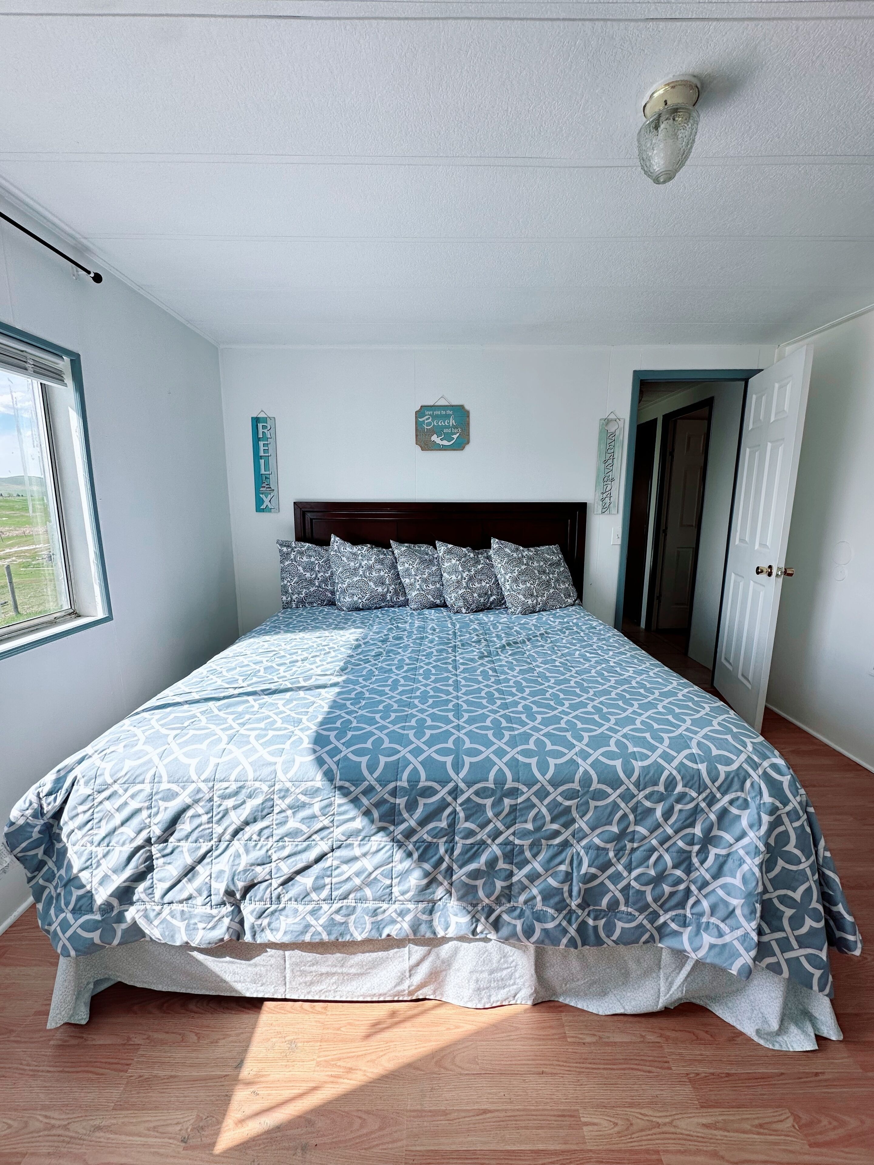 A bedroom with a bed, a window, and a door.