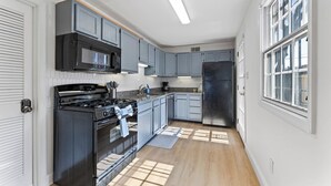 Eine moderne Küche mit grauen Schränken, einem schwarzen Herd und einem Edelstahl-Kühlschrank.