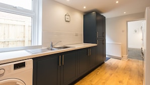 A modern kitchen with dark cabinets, a washing machine, and a window.