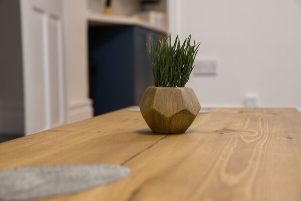 Une table en bois sur laquelle se trouve un vase hexagonal contenant des plantes vertes.