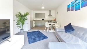 Una sala de estar moderna con un sofá gris, un tapete azul y un televisor de pantalla plana.