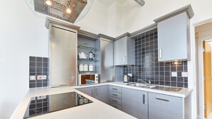 A modern kitchen with a built-in stove, grey cabinets, and a tiled backsplash. - The Loft in Newcastle Upon Tyne (Newcastle-upon-Tyne)