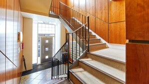 A staircase with wooden walls and a metal railing, leading to a door with a glass panel. - The Loft in Newcastle Upon Tyne (Newcastle-upon-Tyne)